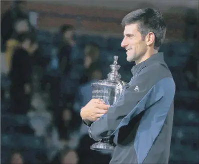  ??  ?? Novak Djokovic cradles the US Open trophy after his straight sets victory over Juan Martin Del Potro in New York.