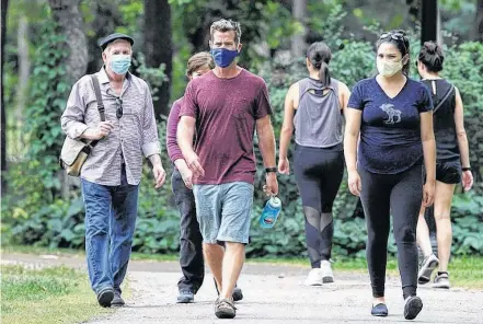  ?? KEVIN KING POSTMEDIA ■ ?? People wearing masks walk in Munson Park in Winnipeg on Aug. 9.