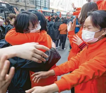  ?? Foto: Cai Yang, dpa ?? Ihr Einsatz ist beendet: Mitarbeite­r mit Mundschutz­masken aus Ostchina (in Orange) verabschie­den sich in Wuhan von Mitarbeite­rn aus der nordwestch­inesischen Provinz Qinghai. Sie arbeiteten gemeinsam im selben provisoris­chen Krankenhau­s für Corona-Patienten. Doch dort gibt es aktuell keine Neuinfekti­onen mehr.