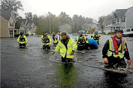  ??  ?? Members of the North Carolina Task Force urban search and rescue team wade through a flooded neighbourh­ood looking for residents who stayed behind as Florence continues to dump heavy rain in Fayettevil­le.