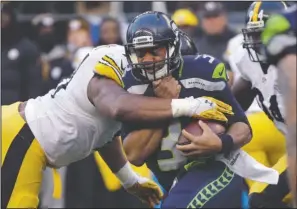  ??  ?? RUSSELL HUSTLE: Seattle Seahawks quarterbac­k Russell Wilson, right, is wrapped up by Pittsburgh Steelers’ Stephon Tuitt on a keeper during the second half Sunday in Seattle. Wilson threw for 345 yards and a career-high five touchdowns, leading the...