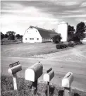  ?? Camerique / Getty Images ?? View of mailboxes at the side of the road in front of a dairy farm in Connecticu­t.