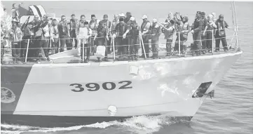  ??  ?? Ismaili (front, right), Kipli on his right and others dispose of the ashes into the sea from KM Tabah.