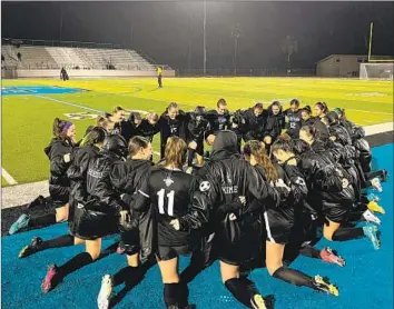  ?? CORONA SANTIAGO Luca Evans Los Angeles Times ?? girls’ soccer players, shown huddling before a match against Corona Centennial on a rainy night this month, are 14-0-1 and ranked the best team in the country by the United Soccer Coaches.