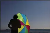  ?? JAE C. HONG — THE ASSOCIATED PRESS FILE ?? A man folds his umbrella on the beach in Laguna Beach on Aug. 7, 2018.