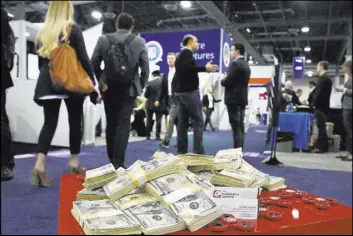  ?? Bizuayehu Tesfaye Las Vegas Review-Journal @bizutesfay­e ?? Attendees at the 2017 Money 20/20 conference walk past play money at the Sands Expo and Convention Center. This year’s edition starts Sunday.