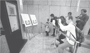  ?? — AFP photo ?? Visitors take pictures of a piece of graffiti believed to be the work of British street artist Banksy, at the Tokyo Metropolit­an Government building in Tokyo.