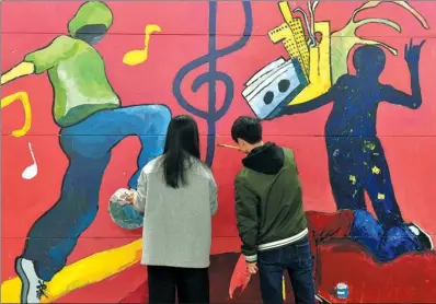  ?? XINHUA ?? Two students paint on the walls of an undergroun­d passageway that links the northern and southern parts of Changzhou University (Baiyun Campus). These young people who study at the university’s school of arts in Jiangsu province spent their free time...