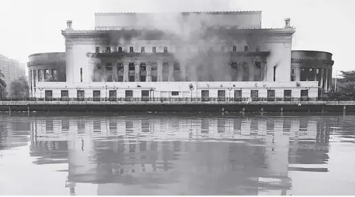  ?? AP ?? Smoke billows from the still smoldering Manila Central Post Office as a fire hits early Monday, May 22, 2023 in Manila, Philippine­s.