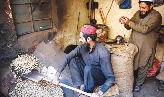  ?? Agence France-presse ?? ↑
A shopkeeper roasts peanuts inside a shop at a market in Peshawar on Saturday.