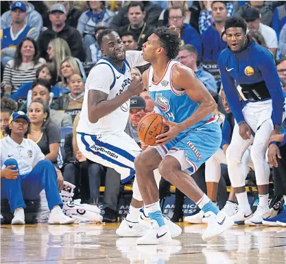  ??  ?? The Kings’ Buddy Hield, right, is defended by the Warriors’ Draymond Green at Oracle Arena.