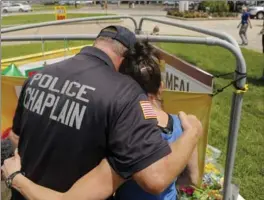  ?? MARK BOSTER, TNS ?? Robert Osler, a police chaplain from New Jersey who came to offer support, comforts resident Stacey DeJohn who brought flowers to a memorial for the slain police officers on Monday.