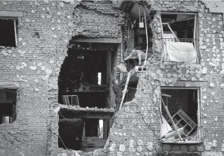  ?? Efrem Lukatsky/Associated Press ?? Residents take out their belongings Saturday from their house ruined by Russian shelling in Irpin, near Kyiv, Ukraine. Russia claims it destroyed a cache of weapons in northern Ukraine.