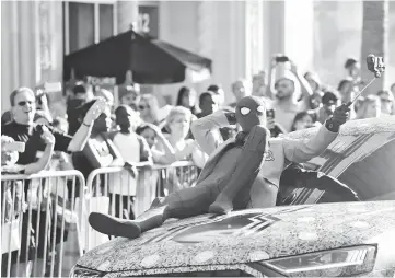  ?? — Reuters photos ?? Fans watch as stars arrive for the World Premiere of ‘Spider-Man: Homecoming’, in Los Angeles, California, on Wednesday. An actor in Spider-Man costume performs for the crowd. (Below) Holland arrives at the premiere.