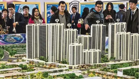  ??  ?? Lack of clarity: A file picture shows prospectiv­e customers looking at a scale model of the Oriental Movie Metropolis at a real estate showroom in Qingdao, China. The Dalian Wanda Group, the parent of the property subsidiary, is among firms that have...