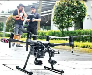  ?? ROSLAN RAHMAN/AFP ?? Staff members of technology firm H3 Dynamics prepare to fly a drone to inspect a building facade in Singapore.