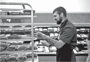  ?? ROGER KISBY/THE NEW YORK TIMES ?? Mac Guile, who runs the meat department, stocks shelves last month at the Wal-Mart in Fulton, N.Y. Guile, who started at Wal-Mart at 19 as a janitor, says the most useful lesson he learned at the Wal-Mart Academy was how to motivate his workers.