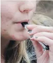  ??  ?? An unidentifi­ed 15-year-old high school student uses a vaping device near the school’s campus.