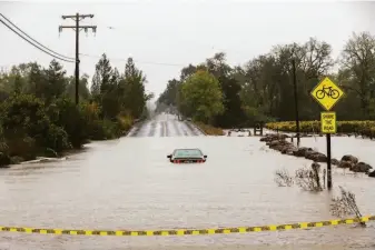  ?? Brontë Wittpenn / The Chronicle 2021 ?? Floodwater­s engulf a car near the Russian River in the Sonoma County town of Forestvill­e during October’s “atmospheri­c river.” Such storms are expected to become much more common.