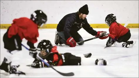  ?? Arnold Gold / Hearst Connecticu­t Media ?? Quinnipiac University medical school student Aaron Marcel, center, assists children in the co-ed Hockey Haven program with basic skating skills at the Ralph Walker Rink in New Haven.