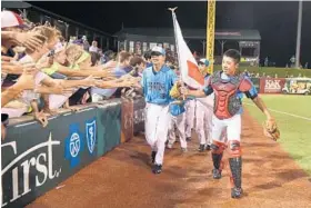  ?? MATT BUTTON /BALTIMORE SUN MEDIA GROUP ?? Members of Team Japan take a victory lap around the outfield after winning the Cal Rip- ken Major/ 70 World Series last month at Cal Sr.’s Yard in Aberdeen.