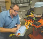  ?? DAX MELMER ?? Ionut Moldoveanu works with a collaborat­ive robot on the shop floor at Radix Inc. in Windsor.