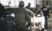  ?? GARCIA/SUN-TIMES ASHLEE REZIN ?? Officers with the U.S. Marshals Service keep watch as Kenosha police officers take a man into custody for violating curfew Thursday night.