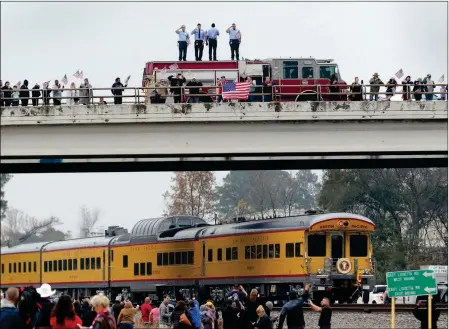  ?? ASSOCIATED PRESS ?? FIREFIGHTE­RS STAND ON THEIR TRUCK AND SALUTE ALONG WITH OTHER ATTENDANTS on an overpass as the train carrying the body of former President George H.W. Bush travels past on the way to Bush’s final internment Thursday in Spring, Texas.