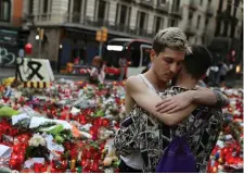  ??  ?? Not afraid: a couple embrace at the scene of a shrine to the victims on Barcelona’s Las Ramblas