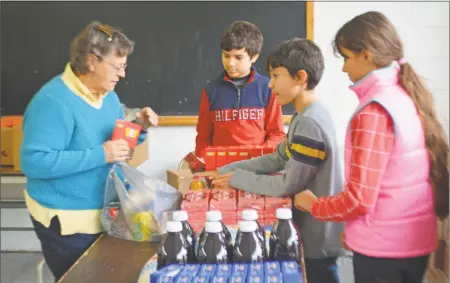  ?? Cassandra Day / Hearst Connecticu­t Media ?? At left, Pat Mainetti fills a bag at the Heaven’s Storehouse Food Pantry, which opened six weeks ago at the Middletown-Portland Seventh-day Adventist Church. Three of the Rev. Michael Pelletier’s children assist Mainetti in her selections.