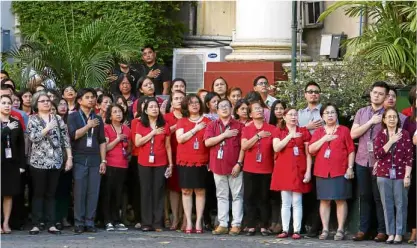  ?? —MARIANNE BERMUDEZ ?? SHOWOF DISMAY With hands on their chests, employees of the Supreme Court wear red during Monday’s flag-raising ceremony to show their dismay over perceived irregulari­ties involving Chief Justice Maria Lourdes Sereno.