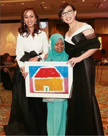  ??  ?? With much love: Tengku Zatashah (left) and Tan receiving a painting by Insyirah during the Wish Ball event at the Mandarin Oriental Hotel in Kuala Lumpur.