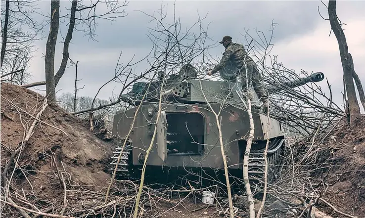  ?? Photo: XInhua ?? A Ukrainian soldier covers an armored vehicle with branches in Donbass on April 12, 2022.