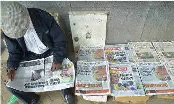  ?? AFP ?? A man reads a local daily next to others with headlines about the situation in Zimbabwe in Nairobi, Kenya, yesterday