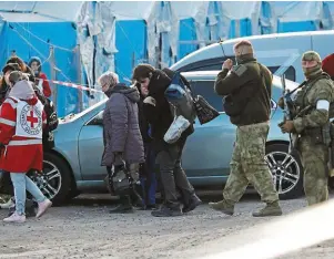  ?? | PHOTO : ALEXANDER ERMOCHENKO, REUTERS ?? Des civils évacués vendredi du complexe sidérurgiq­ue d’Azovstal, escortés par un membre du Comité internatio­nal de la Croix-Rouge, sous l’oeil de soldats russes.