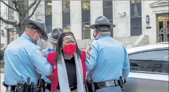  ?? AP PHOTOS ?? State Rep. Park Cannon, D-Atlanta, is placed into the back of a Georgia State Capitol patrol car after being arrested by Georgia State Troopers at the Georgia State Capitol Building in Atlanta, Thursday. Cannon was arrested by Capitol police after she attempted to knock on the door of Gov. Brian Kemp’s office during his remarks after he signed into law a sweeping Republican-sponsored overhaul of state elections that includes new restrictio­ns on voting by mail and greater legislativ­e control over how elections are run.