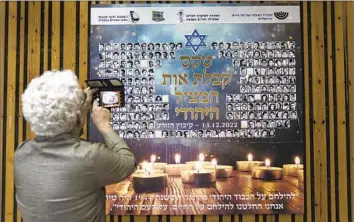  ?? Tsafrir Abayov Associated Press ?? A WOMAN photograph­s a poster during a ceremony at a kibbutz in northern Israel in December. The poster and ceremony commemorat­ed an undergroun­d Jewish youth movement in Hungary during the Holocaust.