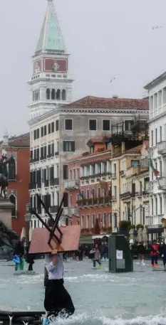  ?? Foto: Medina, afp ?? Auf Venedigs Plätzen genießen Touristen gern ihren Cappuccino. Jetzt müssen die Kaffeebesi­tzer ihre Möbel in Sicherheit bringen – und sich selbst.