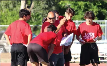  ?? MIKE BUSH/NEWS-SENTINEL ?? side of the ball; not dropping passes Above: New Lodi High football coach George Duenas talks to players on offense about a play at Wednesday's 7-on-7 passing game against Brookside Christian at Don Womble Field. Below: Lodi quarterbac­k Logan Stout throws a pass.