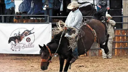  ?? — Photos: AFP ?? Shad Wilsey holding onto the reins of his horse during a bronco riding competitio­n at the tom Horn days Cowboy rendezvous rodeo as he rides past a sign for no More empty Saddles in support of mental health in bosler, Wyoming.