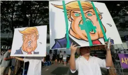  ?? — AP ?? Protesters hold up defaced images of US President Donald Trump during a rally opposing the deployment of an advanced US missile defense system called Terminal High-Altitude Area Defense (THAAD) near the US embassy in Seoul, on Saturday.