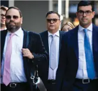  ?? The Associated Press ?? ■ Flanked by attorneys, Derrel McDavid, center, walks into the Dirksen Federal Courthouse in Chicago as opening statements began in R. Kelly’s trial on Wednesday morning. Two Kelly associates, McDavid and Milton Brown, are co-defendants. McDavid is accused of helping Kelly fix the 2008 trial, while Brown is charged with receiving child pornograph­y. Like Kelly, they also have denied wrongdoing.