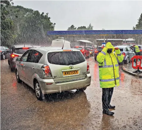  ?? ?? An attendant struggles to direct traffic queuing for fuel at a Tesco petrol station in Ely, Cambs, yesterday