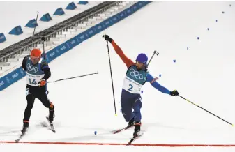  ?? James Hill / New York Times ?? Martin Fourcade of France, the world’s No. 1 biathlete, slides a ski over the finish line to pass Simon Schempp of Germany to win the biathlon 15-kilometer mass start.