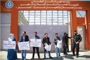  ?? —AFP ?? GAZA: Palestinia­ns demonstrat­e outside an Interior Ministry building in Gaza City, run by Hamas, as they carry signs condemning ‘collaborat­ors and spies’ working for Israel.