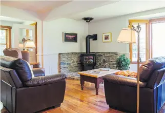  ??  ?? The stone wall and hearth surroundin­g the propane stove in the corner of the living room was built by owner Mike Stone. Future owners will be able to install a wood-burning stove if desired.