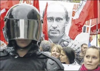  ?? DMITRY LOVETSKY / ASSOCIATED PRESS ?? Protesters hold a poster depicting Russia’s President Vladimir Putin as they march Saturday during a protest rally in St. Petersburg, Russia. The sign reads: “Prices, tariffs and poverty rise, you chose all this.” Thousands of protesters marched in the...