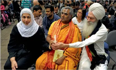  ?? Reuters ?? A Muslim, a Hindu and a Sikh share a candle during a vigil for Srinivas Kuchibhotl­a at a conference centrE in Olathe, Kansas. —