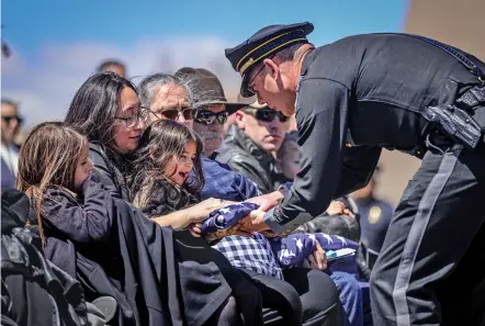  ?? ?? ABOVE: The late Justin Hare’s girlfriend, Daizzare Quintana, and two young daughters, Juliann and Caydence Hare, are presented with a U.S. flag from New Mexico State Police Chief Troy Weisler following Officer Justin Hare’s funeral service at Legacy Church in Albuquerqu­e on Wednesday.