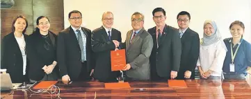  ??  ?? Kadim (fifth right) exchanges documents with Dr Chin after a simple signing ceremony.